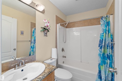 Bathroom featuring a vanity with a granite-style countertop, a white oval undermount sink, and a brushed nickel faucet - 7622 168A Avenue, Edmonton, AB - Indoor Photo Showing Bathroom