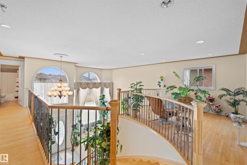 Upper-level landing featuring hardwood flooring, an open staircase with decorative wrought iron spindles, and natural wood handrails - 7622 168A Avenue, Edmonton, AB - Indoor Photo Showing Other Room