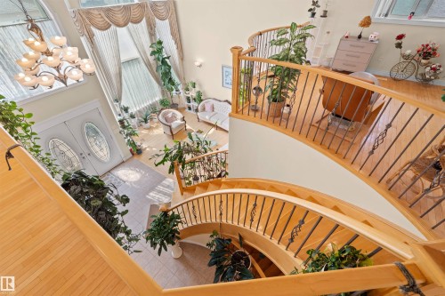 Grand foyer featuring a light wood-finish double staircase with wrought iron balusters and a double-door entry with decorative glass - 7622 168A Avenue, Edmonton, AB - Indoor Photo Showing Other Room