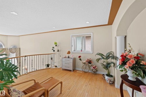 Open upper-level landing featuring wood-finish flooring, a decorative metal and wood railing, recessed lighting, and a window with white trim - 7622 168A Avenue, Edmonton, AB - Indoor Photo Showing Other Room