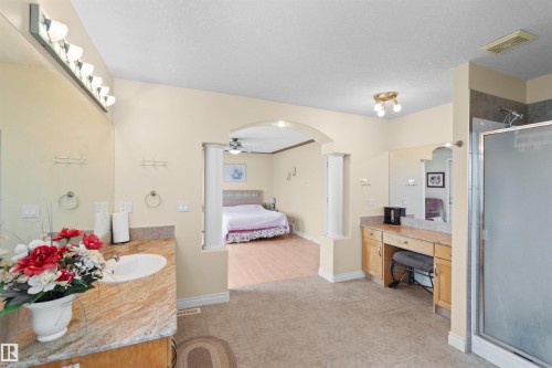 Spacious bathroom featuring a dual vanity, a built-in makeup vanity, a glass-enclosed shower, and tile flooring - 7622 168A Avenue, Edmonton, AB - Indoor Photo Showing Bathroom
