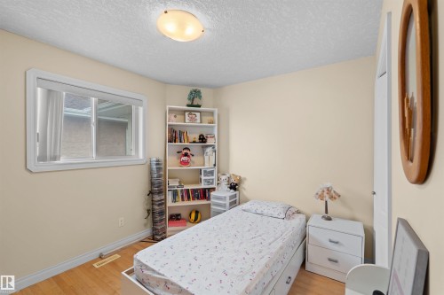 Light-toned walls complement wood-finish flooring in this room featuring a white-framed window and a flush-mount ceiling light - 7622 168A Avenue, Edmonton, AB - Indoor Photo Showing Bedroom