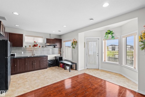 Open-concept kitchen and dining area featuring dark wood-finish cabinetry, a tile backsplash, and recessed lighting - 7622 168A Avenue, Edmonton, AB - Indoor Photo Showing Kitchen