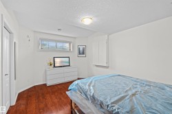 Room featuring wood-finish flooring, a white trim baseboard, and white painted walls - 