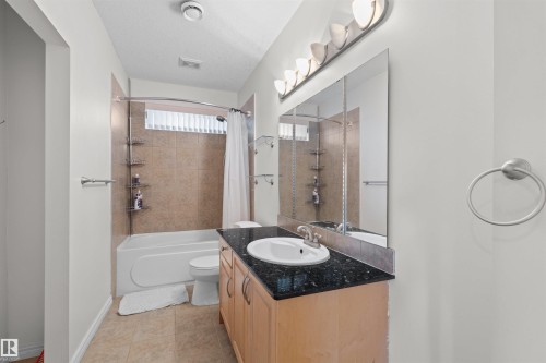 Bathroom featuring a wood-finish vanity with a dark countertop and an undermount sink - 7622 168A Avenue, Edmonton, AB - Indoor Photo Showing Bathroom