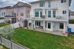 Rear exterior featuring a ground-level patio, upper-level balcony with glass railing, and a second-story balcony - 