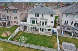 Rear exterior of a two-story residence featuring a gray shingle roof and stucco siding - 