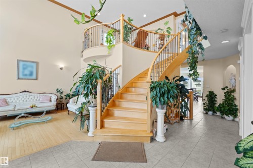Grand foyer featuring a curved staircase with natural wood treads and wrought iron balusters - 7622 168A Avenue, Edmonton, AB - Indoor Photo Showing Other Room