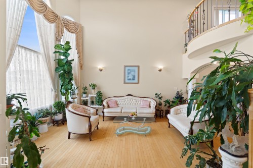 Two-story living area featuring light wood-finish flooring, a grand two-story window with drapery, and a curved second-story balcony with wrought iron railing - 7622 168A Avenue, Edmonton, AB - Indoor