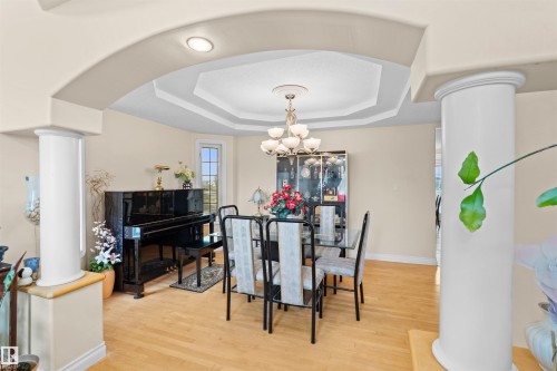 Dining area featuring wood-finish flooring, a tray ceiling with a chandelier, and a bay window - 7622 168A Avenue, Edmonton, AB - Indoor Photo Showing Dining Room