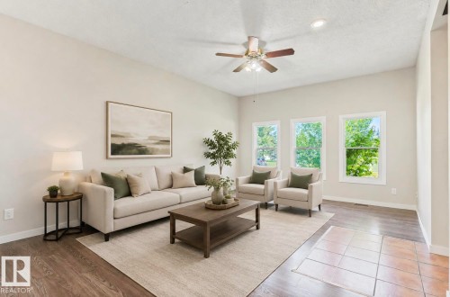 Spacious living area featuring wood-finish flooring, ample natural light from multiple windows, recessed lighting, and a ceiling fan - 10211 95 Ave, Morinville, AB - Indoor Photo Showing Living Room