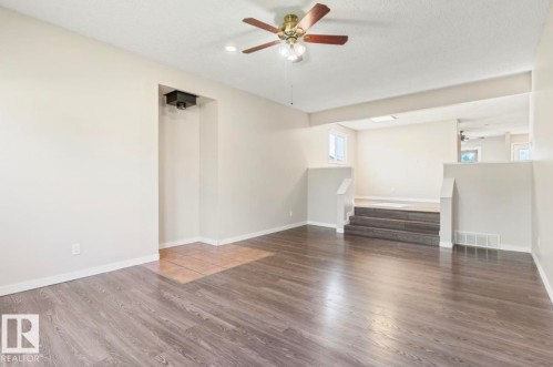 Spacious room featuring wood-finish flooring, a ceiling fan with integrated lighting, and recessed lighting - 10211 95 Ave, Morinville, AB - Indoor Photo Showing Other Room