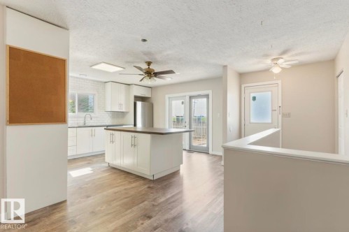 Kitchen with white cabinetry, dark countertops, and wood-finish flooring - 10211 95 Ave, Morinville, AB - Indoor Photo Showing Kitchen