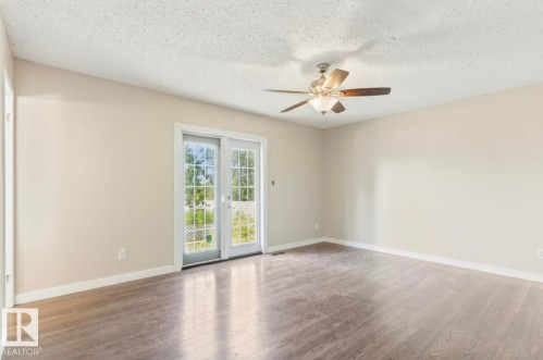 Spacious room featuring wood-finish flooring, light-toned walls, and a ceiling fan with integrated lighting - 10211 95 Ave, Morinville, AB - Indoor Photo Showing Other Room