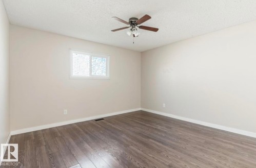 Spacious room featuring wood-finish flooring, light-toned walls, and a ceiling fan with integrated lighting - 10211 95 Ave, Morinville, AB - Indoor Photo Showing Other Room