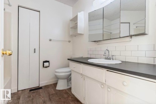 Bathroom featuring a white vanity with dark countertop, subway tile backsplash, and mirrored medicine cabinet - 10211 95 Ave, Morinville, AB - Indoor Photo Showing Bathroom
