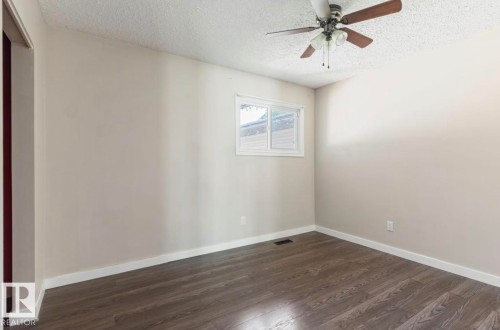 Room featuring wood-finish flooring, neutral wall tones, and white baseboards - 10211 95 Ave, Morinville, AB - Indoor Photo Showing Other Room