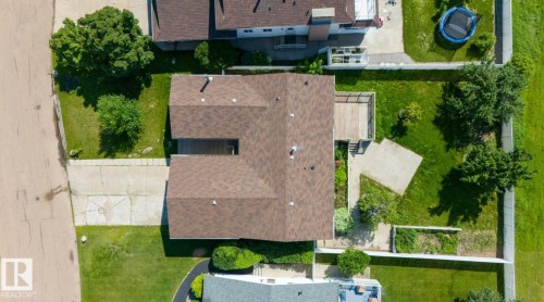 Shingle roof property with a spacious backyard featuring a wooden deck, concrete patio, and mature trees - 10211 95 Ave, Morinville, AB - Outdoor