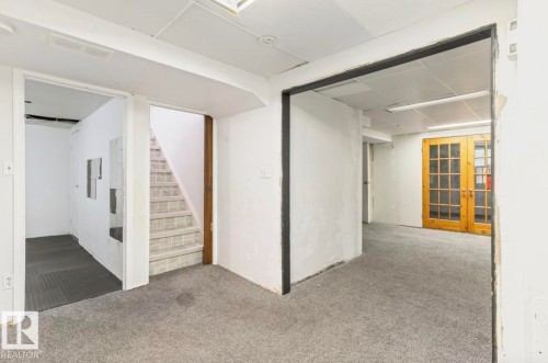 Carpeted floor in a neutral tone with white walls, drop ceiling, and exposed doorway framing - 10211 95 Ave, Morinville, AB - Indoor