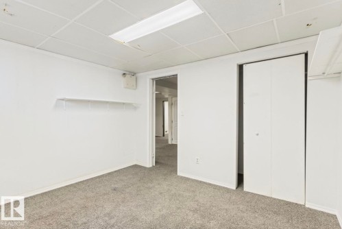 Carpeted room with white walls, drop ceiling, and flush-mounted fluorescent lighting - 10211 95 Ave, Morinville, AB - Indoor Photo Showing Other Room