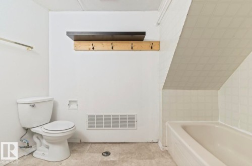 Bathroom featuring a white toilet, white bathtub with tiled surround, and light-toned flooring - 10211 95 Ave, Morinville, AB - Indoor Photo Showing Bathroom