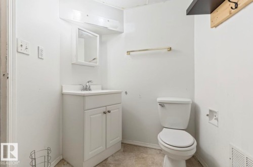 Bathroom featuring a white vanity with a laminate countertop, a mirrored medicine cabinet, a two-piece toilet, and tile flooring - 10211 95 Ave, Morinville, AB - Indoor Photo Showing Bathroom