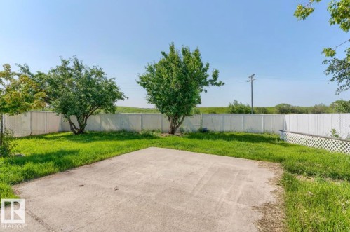 Expansive backyard featuring a concrete patio, a manicured lawn, and mature trees - 10211 95 Ave, Morinville, AB - Outdoor With Backyard