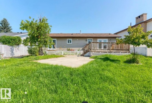 Rear exterior featuring a wooden deck with lattice skirting, double French doors, and a concrete patio - 10211 95 Ave, Morinville, AB - Outdoor With Deck Patio Veranda