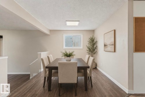 Dining area featuring wood-finish flooring, a white window frame, square ceiling light fixture, and neutral painted walls - 10211 95 Ave, Morinville, AB - Indoor Photo Showing Dining Room