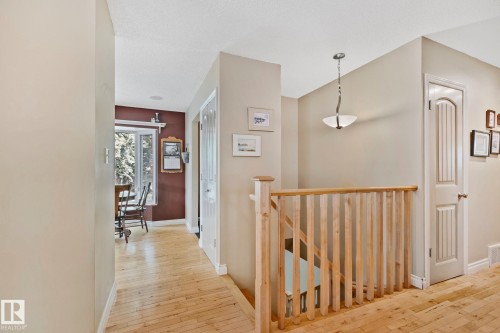Hallway featuring wood-finish flooring, a wood banister, and a semi-flush mount light fixture - 7306 21 Avenue Nw, Edmonton, AB - Indoor Photo Showing Other Room