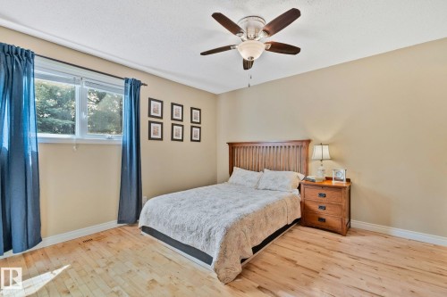 Spacious room featuring light wood-finish flooring, a contemporary ceiling fan with integrated lighting, and a large window providing natural illumination - 7306 21 Avenue Nw, Edmonton, AB - Indoor Photo Showing Bedroom