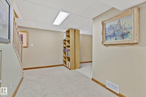 Carpeted floor area with a drop ceiling and integrated fluorescent lighting - 7306 21 Avenue Nw, Edmonton, AB - Indoor Photo Showing Other Room