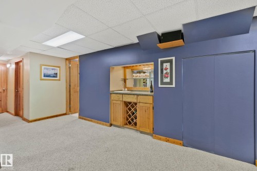Built-in wet bar featuring a stone-finish countertop, wood cabinetry, and integrated wine storage - 7306 21 Avenue Nw, Edmonton, AB - Indoor