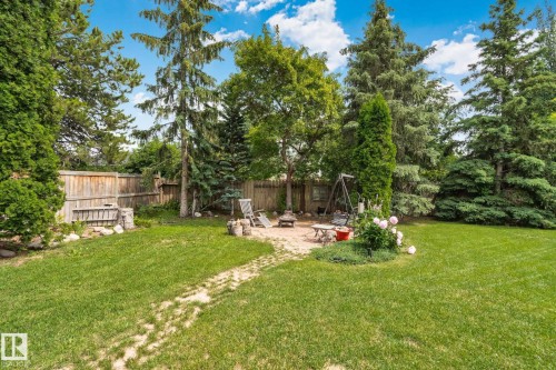 Expansive backyard featuring a large lawn area, mature trees, and a wooden privacy fence - 7306 21 Avenue Nw, Edmonton, AB - Outdoor