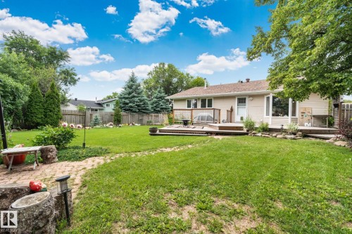 Spacious rear yard with a multi-level wood deck, established trees, and a brick paver pathway - 7306 21 Avenue Nw, Edmonton, AB - Outdoor With Deck Patio Veranda