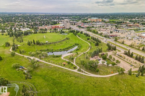 Expansive parkland featuring extensive green spaces, a meandering pond, paved walking paths, numerous mature trees, and nearby commercial developments - 7306 21 Avenue Nw, Edmonton, AB - Outdoor With View