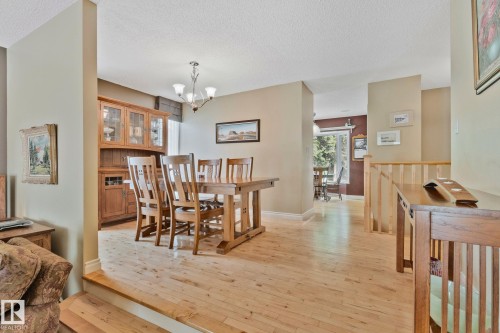Bright dining area featuring wood-finish flooring, a contemporary chandelier, and built-in cabinetry - 7306 21 Avenue Nw, Edmonton, AB - Indoor Photo Showing Dining Room