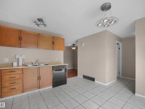 Kitchen area featuring light wood cabinetry, a dual-basin stainless steel sink, and a black built-in dishwasher - 3509 43A Avenue Nw, Edmonton, AB - Indoor Photo Showing Kitchen With Double Sink