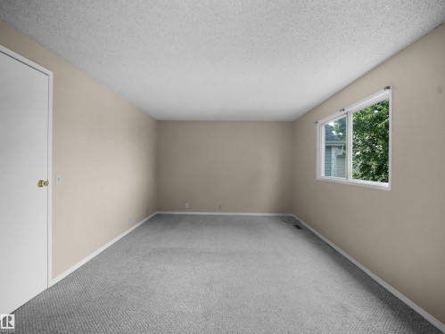 Interior room featuring neutral wall paint, grey carpeting, a single white window with exterior greenery, a popcorn ceiling, and white trim - 3509 43A Avenue Nw, Edmonton, AB - Indoor Photo Showing Other Room