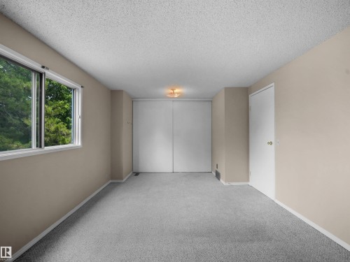 Carpeted room featuring a large window, neutral wall paint, white trim, and a ceiling-mounted light fixture - 3509 43A Avenue Nw, Edmonton, AB - Indoor Photo Showing Other Room