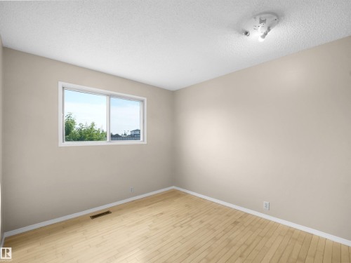 Light-filled room featuring wood-finish flooring, neutral wall paint, and a white trim window - 3509 43A Avenue Nw, Edmonton, AB - Indoor Photo Showing Other Room