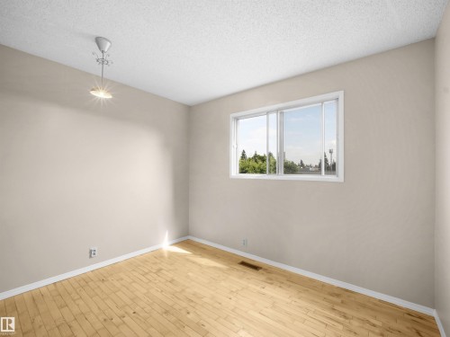 Interior room featuring wood-finish flooring, light-colored walls, white baseboards, and a sliding window with a white frame - 3509 43A Avenue Nw, Edmonton, AB - Indoor Photo Showing Other Room