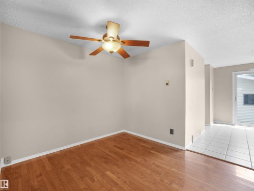 Neutral-toned room featuring a wood-finish floor and a ceiling fan with integrated lighting - 3509 43A Avenue Nw, Edmonton, AB - Indoor Photo Showing Other Room