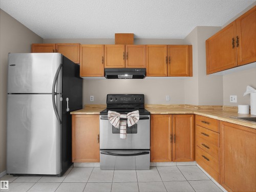 Kitchen featuring wood-finish cabinetry, stainless steel appliances, and light-toned countertops - 3509 43A Avenue Nw, Edmonton, AB - Indoor Photo Showing Kitchen