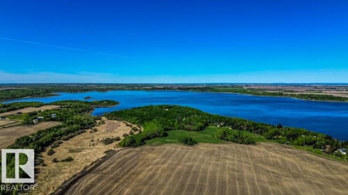Expansive waterfront property featuring a large body of water, wooded shoreline, open fields, and distant agricultural lands under a clear blue sky - 705 59128 Rng Rd 95, Rural St. Paul County, AB 