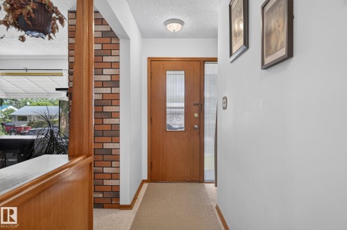 Warm wood-finish entry door with a frosted glass insert, flanked by a frosted glass sidelight - 12908 104 Street Nw, Edmonton, AB - Indoor Photo Showing Other Room