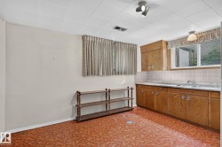 Kitchenette featuring wood-finish cabinetry, a single basin sink, white countertops, and a tiled backsplash - 