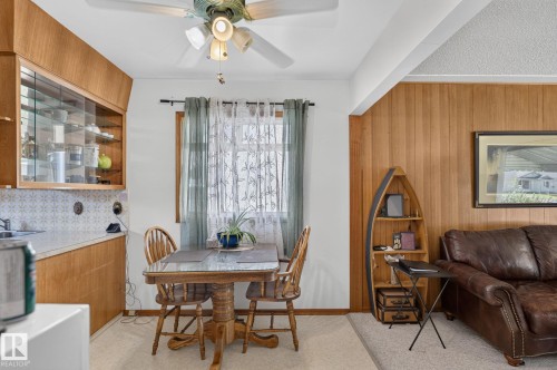 Dining area featuring a wood-finish table, a window with sheer and solid curtains, and a ceiling fan with integrated lighting - 12908 104 Street Nw, Edmonton, AB - Indoor Photo Showing Dining Room