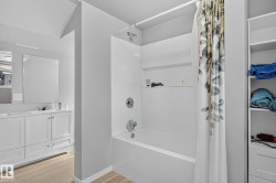 Bathtub with white tile surround and integrated shelving, featuring a chrome shower head and faucet - 