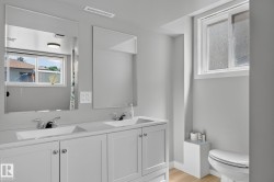 Bathroom featuring a dual-sink vanity with white cabinetry, chrome faucets, and two large mirrors - 